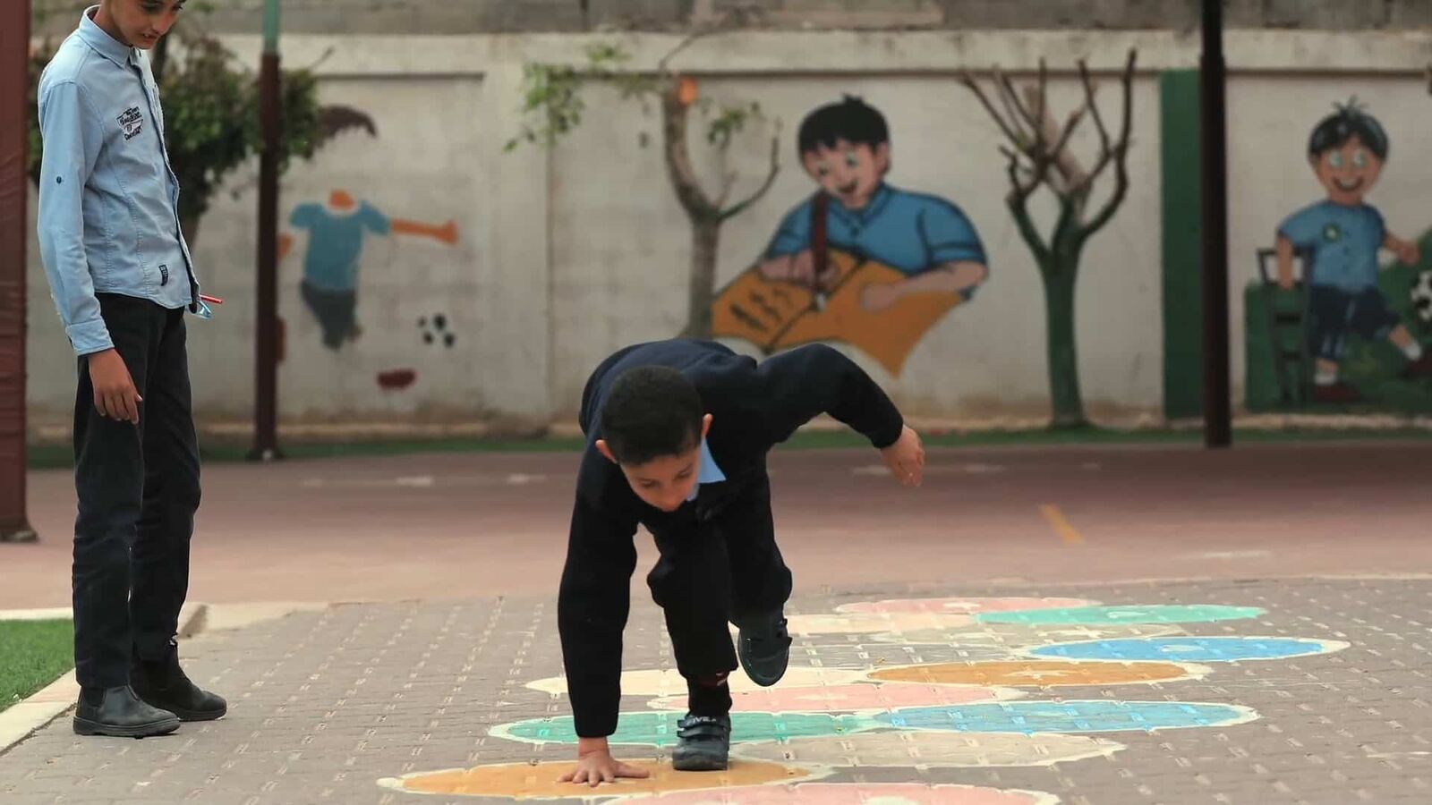 Children play outdoors in the sun; one tumbles upside-down.